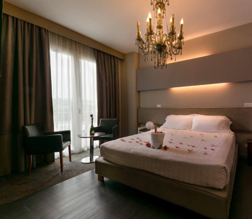 Camera elegante con letto matrimoniale, lampadario e arredamento moderno.